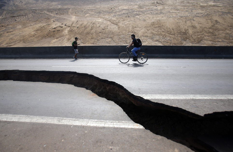 29. Two men pass by a crack in a highway between the areas of Iquique and Alto Hospicio, Chile - April 3, 2014.