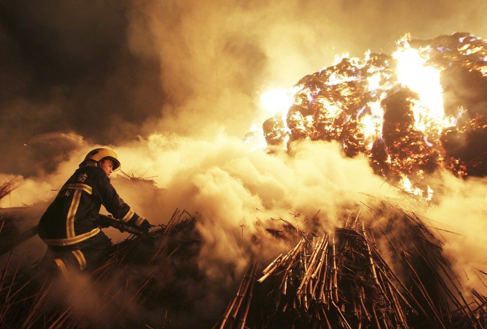 32. A firefighter attempts to extinguish a fire that broke out on piles of canes at a paper factory in Changde, Hunan province, China - February 16, 2014.