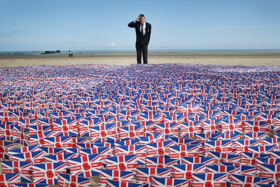 47. WWII veteran Fred Holborn, from the Fleet Air Arm, salutes as he looks at British Legion Union flags carrying thank you messages planted in the sand on Gold Beach