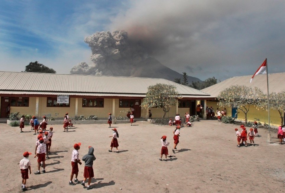 49. Students play in their school yard as Mount Sinabung erupts in Sukandebi, North Sumatra, Indonesia - January 16, 2014.