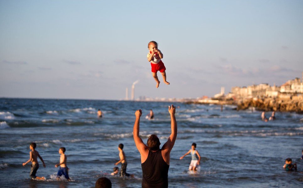53. A Palestinian man plays with his baby on the beach of Gaza city - September 7, 2014.
