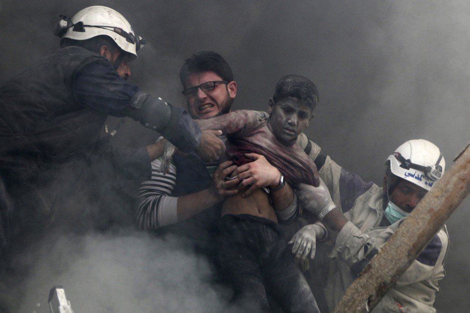 89. Men rescue a boy after forces loyal to Syria’s President Bashar Al-Assad bombed Aleppo - April 6, 2014.