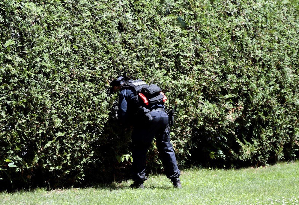 An officer checks a bush during a door-to-door search for two escaped prisoners from Clinton Correctional Facility in Malone, New York – June. 24, 2015