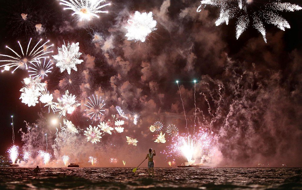 A man rides a stand up paddle board as fireworks explode above him during New Year's festivities on Copacabana Beach, Rio de Janeiro, Brazil – Jan. 1, 2015