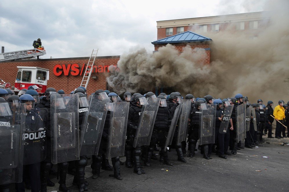 Baltimore police form a perimeter around a CVS pharmacy that was plundered and torched during the riots – April 27, 2015.