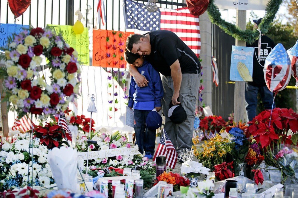 Father and son pay their respects at a makeshift memorial site to honor the shooting victims in San Bernardino, California – Dec. 9, 2015