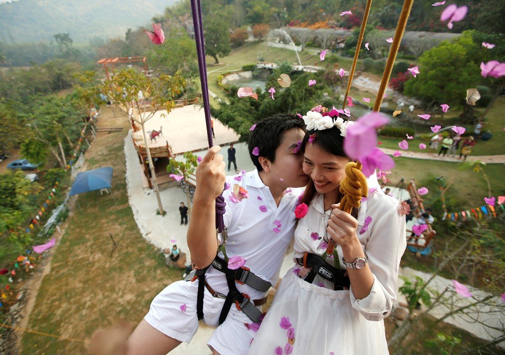 Newly married Thai couple is suspended from ropes during their rock climbing wedding ceremony in Thailand – Feb. 13, 2015.