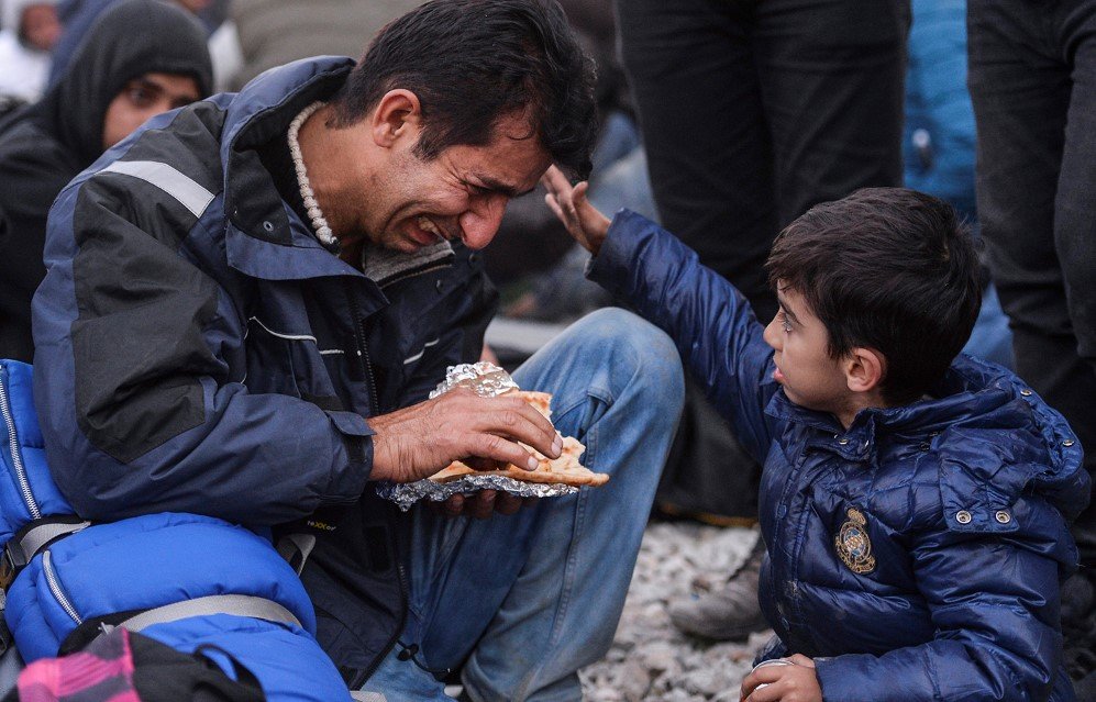 A small boy caresses his crying father during a protest by migrants from Pakistan and Morocco in Macedonia – Nov. 19, 2015.