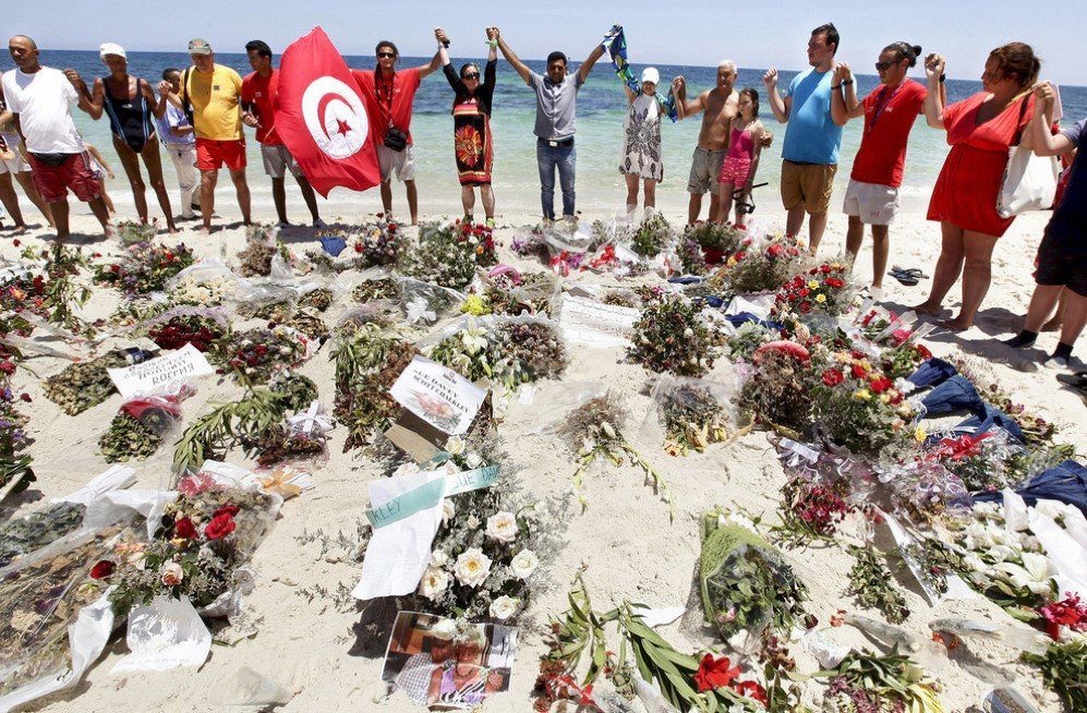 People join hands as they observe a minute’s silence in memory of those killed in an attack at a beach in Sousse, Tunisia – July 3, 2015