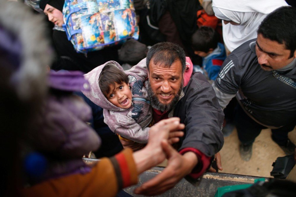 a displaced iraqi with his son prepares to get on a truck to be carried to a safe place as iraqi forces battle with islamic state militants in western mosul iraq on march 8 2017