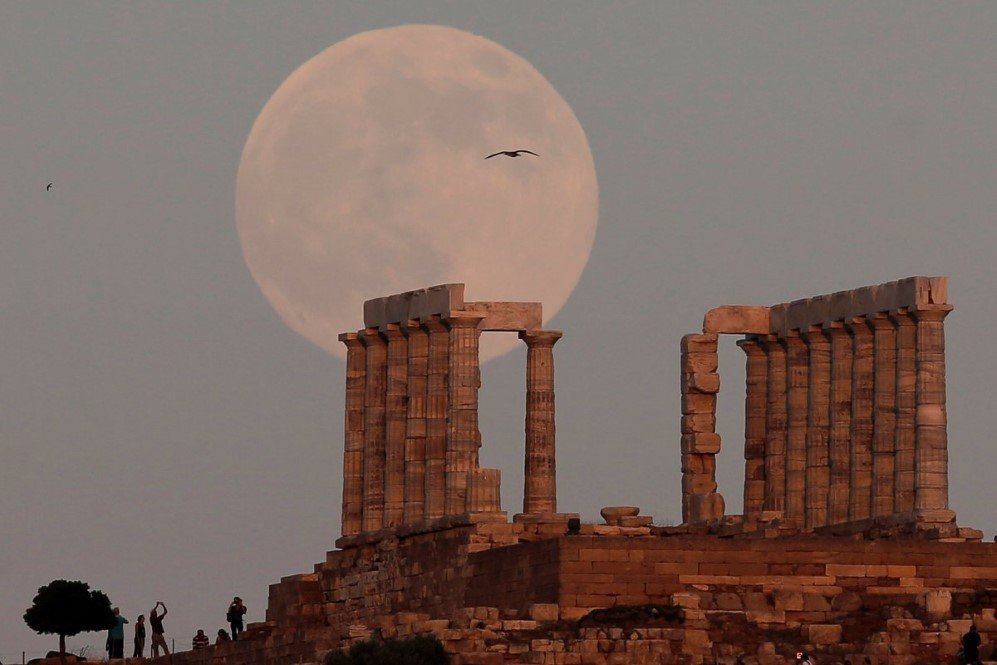 a full moon rises over the temple of poseidon the ancient greek god of the seas in cape sounion east of athens greece on july 8 2017
