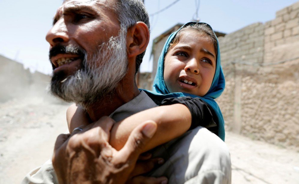 a man carries his daughter on his back after fleeing their home due to fighting between the iraqi forces and islamic state militants in mosuls al zanjilis district in iraq on june 7 2017