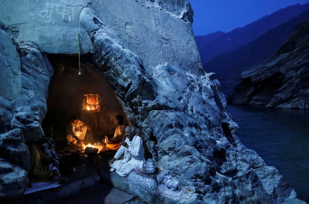 hindu priests sit inside a cave as they perform evening prayers on the banks of the river ganges in devprayag india on march 28 2017