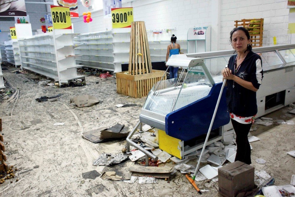 workers clean the floor next to empty shelves and refrigerators in a supermarket after it was looted in san cristobal venezuela on may 17 2017