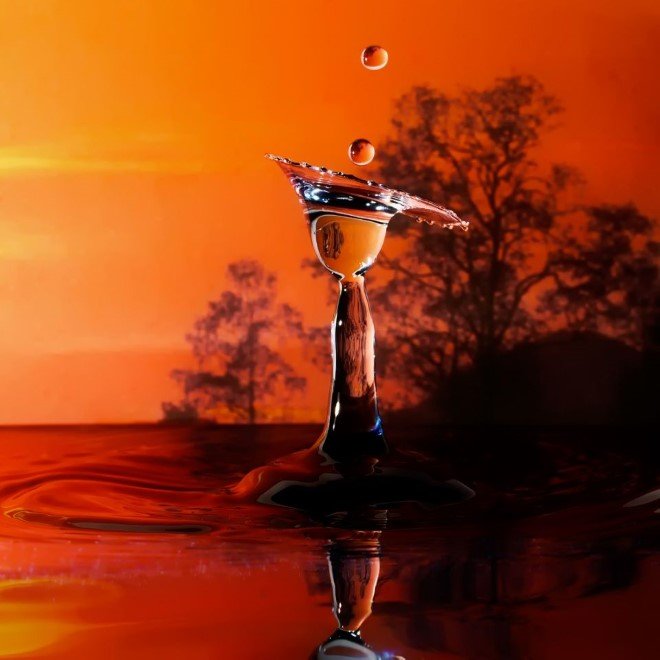 A droplet with trees at sunset behind.